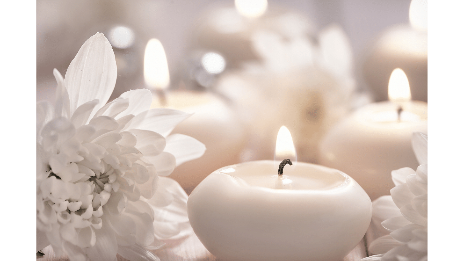 Aromatherapy candles surrounded by white flowers, promoting relaxation and tranquility.